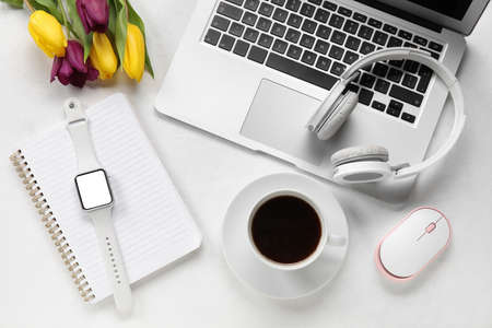Composition with cup of coffee, notebook and gadgets on light background