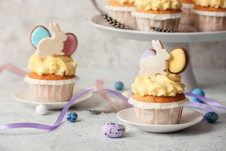 Tasty Easter cupcakes and eggs on light background, closeup