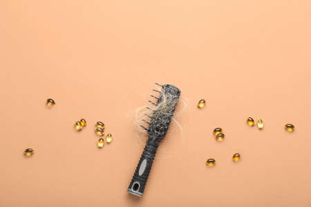 Brush with fallen down hair and pills on beige backgroundの写真素材