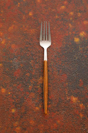 Stylish stainless steel fork on grunge background