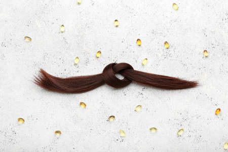 Brunette hair strand with pills on grunge background