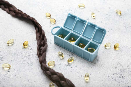 Container with pills and hair strand on grunge backgroundの写真素材