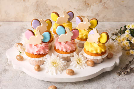 Board with tasty Easter cupcakes, eggs and flowers on light backgroundの写真素材