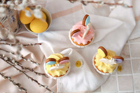 Tasty Easter cupcakes with eggs and willow branches on color backgroundの写真素材