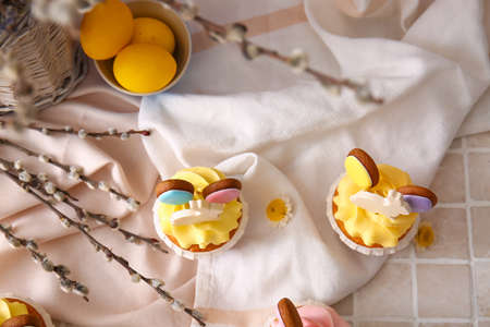 Tasty Easter cupcakes with eggs and willow branches on color backgroundの写真素材