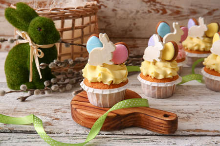 Tasty Easter cupcakes on light wooden table