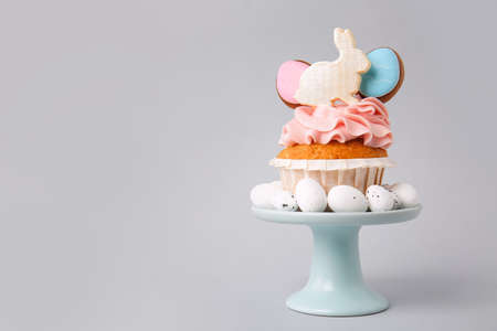 Stand with tasty Easter cupcake and eggs on gray backgroundの写真素材