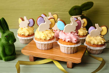 Board with tasty Easter cupcakes on wooden table