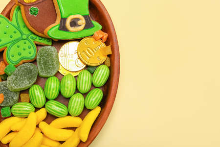 Plate with different sweets for St. Patrick's Day celebration on beige background, closeup
