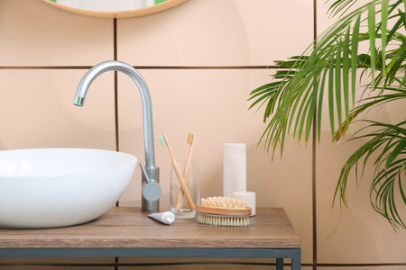 Brushes and jars with cosmetic products on table near sink