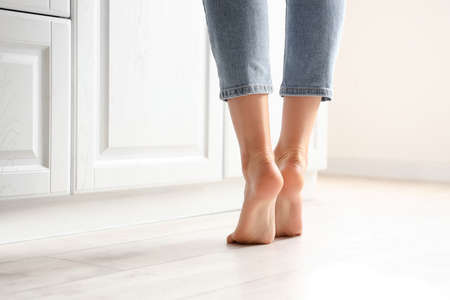 Barefoot woman near counter in kitchen, closeup