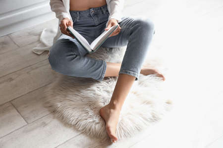 Barefoot woman reading book in kitchen