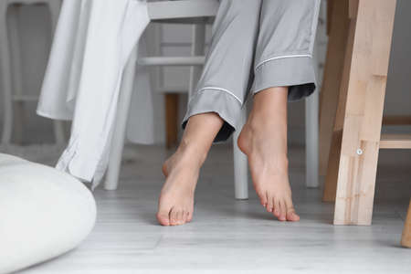 Barefoot woman sitting in chair at home