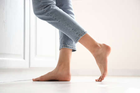 Barefoot woman near counter in kitchen, closeup