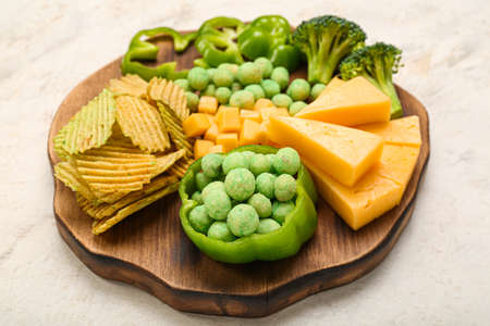 Wooden board with different snacks for St. Patrick's Day celebration on light backgroundの写真素材