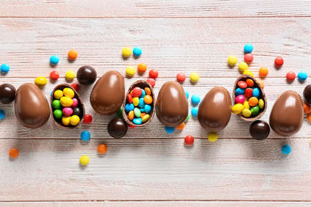 Chocolate Easter eggs with candies on white wooden backgroundの写真素材