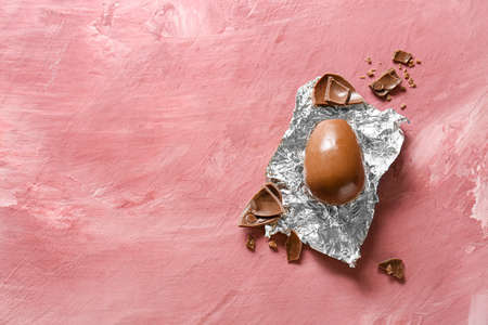 Chocolate Easter egg with foil on pink backgroundの写真素材