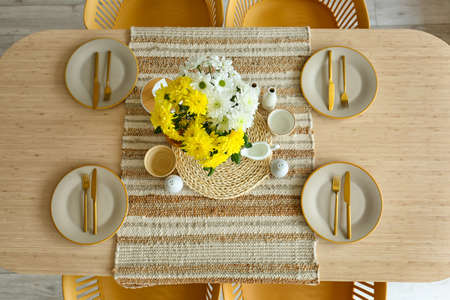 Dining table with setting and flowers in vase served for International Women's Day celebration