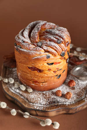 Wooden board with delicious Easter cake and pussy willow branches on brown backgroundの写真素材
