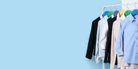 Rack with stylish school uniform near light blue wall. banner designの写真素材