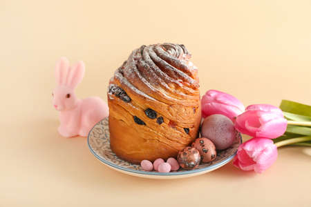 Plate with delicious Easter cake, eggs and tulip flowers on beige background