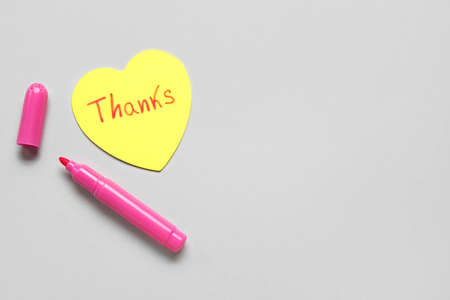 Heart shaped sticky note with word THANKS and felt-tip pen on gray backgroundの写真素材