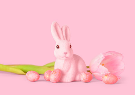 Cute Easter bunny with eggs and flower on pink backgroundの写真素材