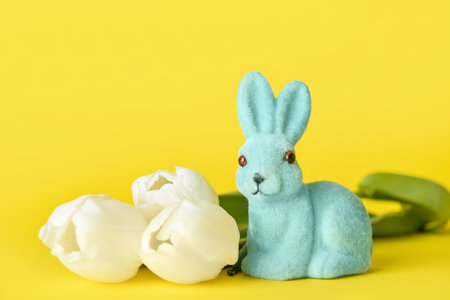Cute Easter bunny with flowers on yellow background