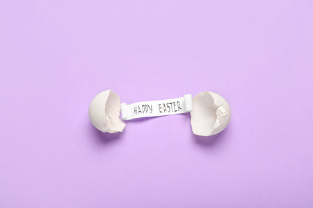 Composition with broken egg and text HAPPY EASTER on purple background