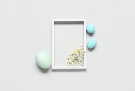 Beautiful composition with frame, Easter eggs and flowers on light backgroundの写真素材