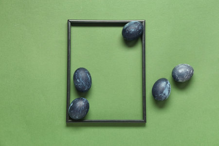 Beautiful composition with frame and Easter eggs on green backgroundの写真素材