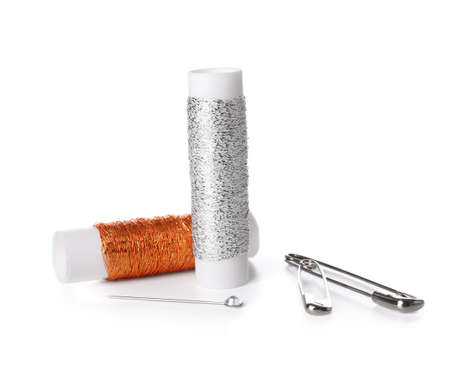 Thread spools, safety pins and ball pins on white background