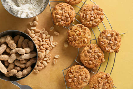 Cooling rack with tasty peanut cookies on yellow background