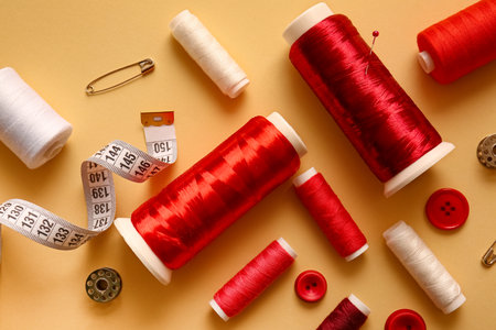 Thread spools, buttons and measuring tape on color backgroundの写真素材