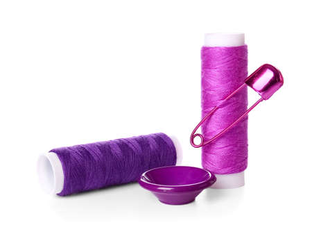 Thread spools, button and safety pin on white background