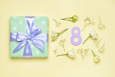 Composition with gift for International Women's Day and flowers on color background