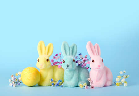 Beautiful Easter bunnies, flowers and painted egg on blue background