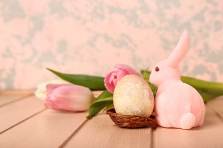 Beautiful Easter bunny, flowers and painted egg on pink wooden tableの写真素材