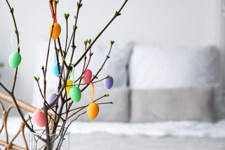 Branches with Easter eggs in interior of bedroom, closeup