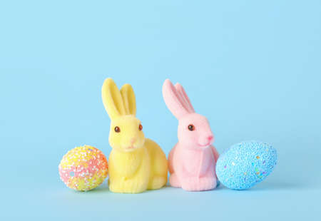 Beautiful Easter bunnies and painted eggs on blue background