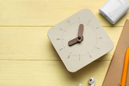 Alarm clock and earphones on wooden background, closeup