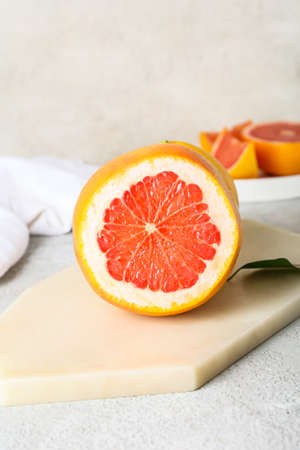 Board with tasty cut grapefruit on light backgroundの写真素材