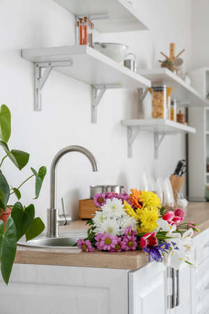 Modern light kitchen with bouquet of flowers in sinkの写真素材