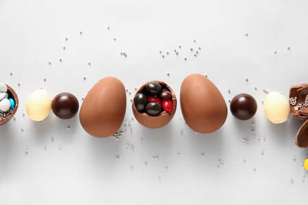 Composition with chocolate Easter eggs and different candies on light background