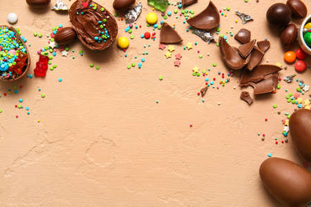 Composition with broken chocolate Easter eggs and different candies on beige backgroundの写真素材