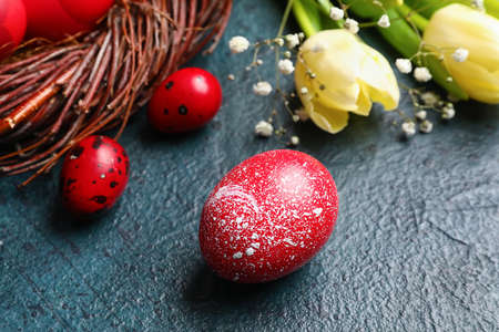 Red painted Easter egg and flowers on dark background