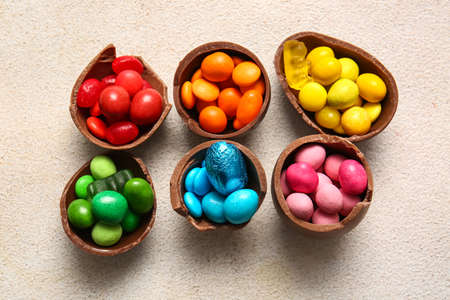 Broken chocolate Easter eggs and different candies on light backgroundの写真素材