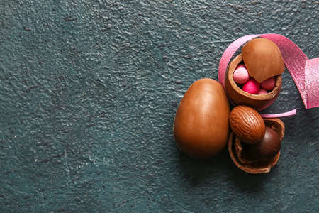 Broken chocolate Easter eggs and candies on dark background