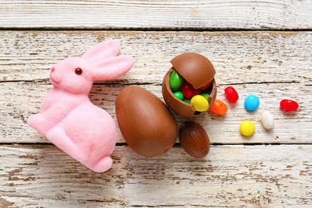 Chocolate Easter eggs with different candies and bunny on light wooden backgroundの写真素材