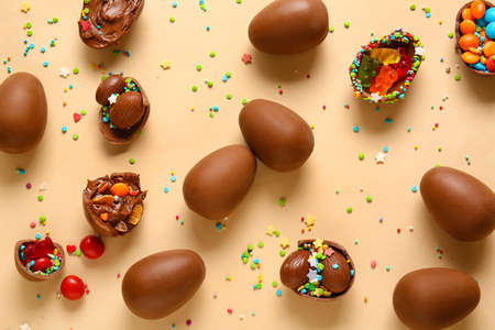 Composition with chocolate Easter eggs, different candies and sprinkles on beige backgroundの写真素材